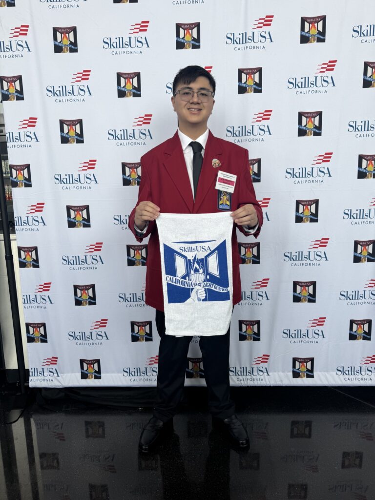JC at SkillsUSA California holding up a blue and white banner.