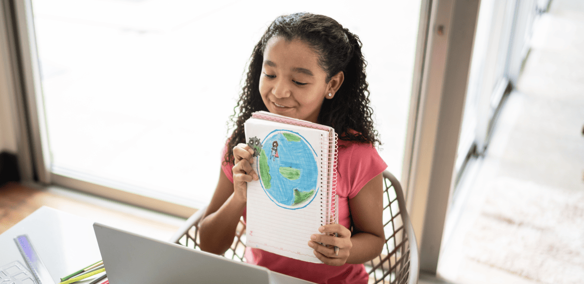 A girl holds a notebook featuring a globe design, symbolizing exploration and knowledge.