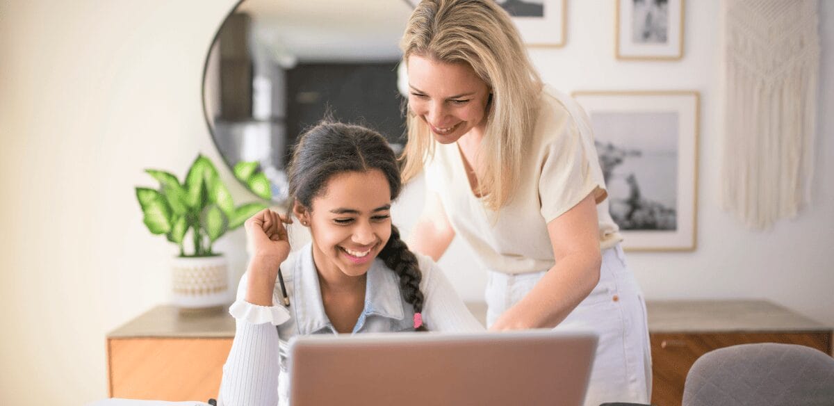 A woman and a young girl collaborate on a laptop, engaged in a productive learning experience together.