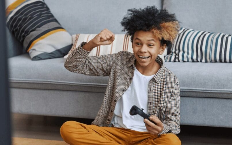 A young boy sits on the floor, focused on a game controller in his hands, surrounded by a playful atmosphere.
