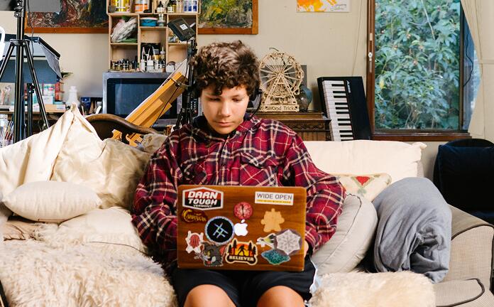 Student sitting on his couch working with his laptop