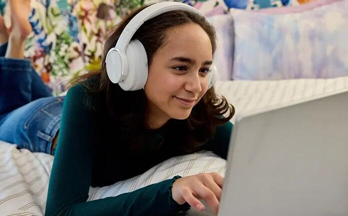 High school student attending to an online class wearing a white pair of headphones